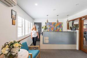 a woman walking through a room with a table and chairs at Panorama Bathurst in Bathurst