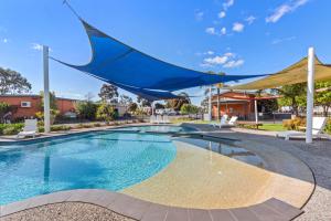 a swimming pool with a blue umbrella over it at Discovery Parks - Melbourne in Braybrook