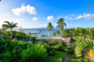 a view of the ocean from a resort with palm trees at Hotel Bakoua Martinique in Les Trois-Îlets