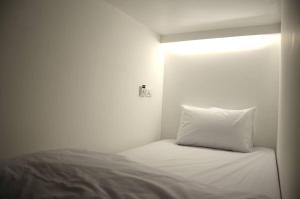 a white bed with a white comforter and pillows at 3Howw Hostel @ Sukhumvit 21 in Bangkok