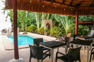 a patio with tables and chairs and a swimming pool at Tulum Nah in Tulum