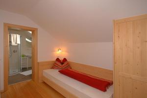Un dormitorio con un banco con una manta roja. en Ferienwohnungen Bulandhof, en Valdaora