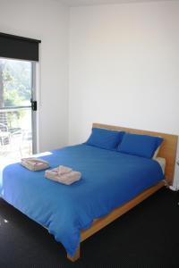a bed with blue sheets and two towels on it at Craggy Peaks in Rossarden