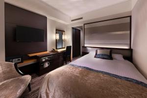 a hotel room with a bed and a flat screen tv at Hotel Granvia Okayama in Okayama