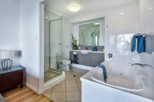 a bathroom with a tub and a toilet and a sink at Sea View Shorelines Hamilton Island in Hamilton Island
