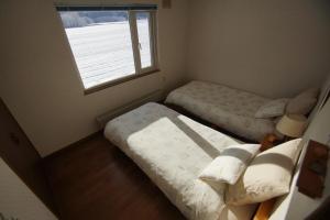 ein kleines Schlafzimmer mit 2 Betten und einem Fenster in der Unterkunft Farm Stay Ezura Farm in Engaru