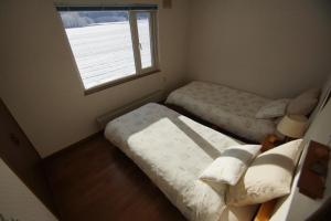 a small bedroom with two beds and a window at Farm Stay Ezura Farm in Engaru