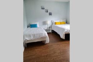 a white bedroom with two beds and a lamp at Cottage with River Front & minutes away from Beach in Wasaga Beach