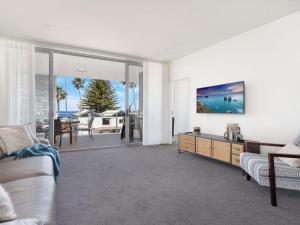 a living room with a couch and a table with a tv at Bathers at the Beach in Kiama