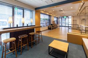a lobby with a bar with stools and tables at The OneFive Fukuoka Tenjin in Fukuoka