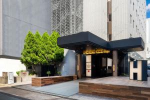 a building with a black awning on a street at The OneFive Fukuoka Tenjin in Fukuoka