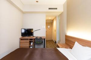 a hotel room with a bed and a television at The OneFive Fukuoka Tenjin in Fukuoka