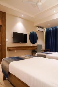 a hotel room with two beds and a flat screen tv at Cosmique Clarks Inn Suites Goa in Madgaon