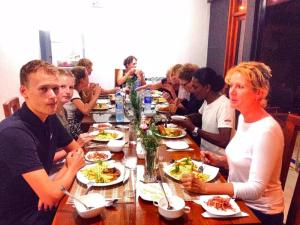 Eine Gruppe von Menschen, die an einem Tisch sitzen und Essen essen. in der Unterkunft Grace Holiday Bungalow in Haputale
