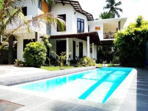 a villa with a swimming pool in front of a house at Om Villa in Hikkaduwa