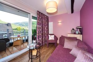 a living room with a purple couch and a balcony at Hotel Halfenstube & Villa Spa 1894 in Senheim