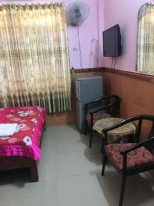 Cette chambre comprend un lit, deux chaises et une télévision. dans l'établissement Bao Vy Hotel, à Hô-Chi-Minh-Ville