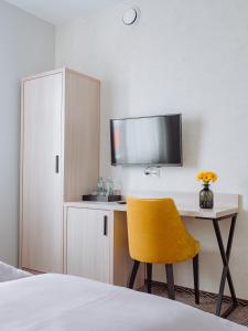 a bedroom with a desk with a yellow chair and a tv at Hotel Chrobrego9 in Bolesławiec