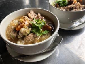 due ciotole di zuppa su un tavolo con un cucchiaio di Resort Railumpoo (Farm and Camping) a Nakhon Sawan