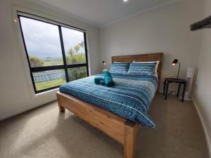 a bedroom with a bed with a blue comforter and a window at Sunset View Villa in Apollo Bay