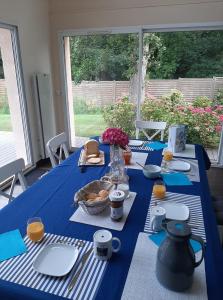 een blauwe tafel met borden en kommen met eten erop bij Chez Blandine & Pol in Hardelot-Plage