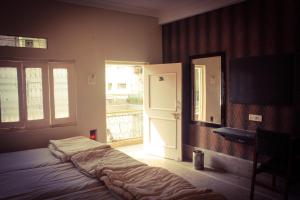 1 dormitorio con cama, ventana y puerta en Hotel Anand Palace, en Gwalior