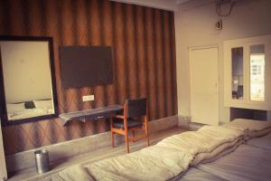 Schlafzimmer mit einem Bett, einem Schreibtisch und einem Spiegel in der Unterkunft Hotel Anand Palace in Gwalior