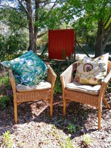 two wicker chairs with pillows sitting in a yard at The Red Gate Suite for Garden Route tranquility in George