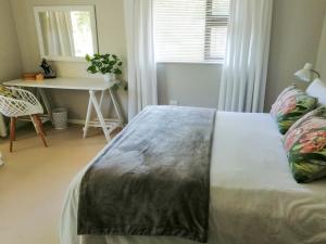 a bedroom with a bed with a table and a window at The Red Gate Suite for Garden Route tranquility in George