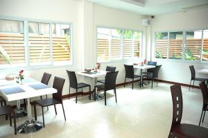 un ristorante con tavoli e sedie bianchi e finestre di Calypzo 2 Ratchada 20 a Bangkok