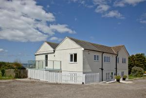 a white house with a fence in front of it at Blue Bay, Marazion in Perranuthnoe