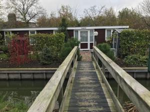 a house on a wooden boardwalk next to a bridge at Houseboat Linquenda in Woubrugge