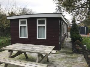 a small cabin with a picnic table on a deck at Houseboat Linquenda in Woubrugge