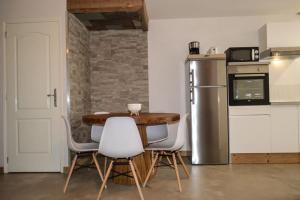 eine Küche mit einem Tisch und Stühlen sowie einem Kühlschrank in der Unterkunft L'Ecureuil in Barbey-Séroux