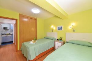 two beds in a room with yellow walls and a kitchen at Apartment Tindaya MT Maspalomas by VillaGranCanaria in Maspalomas