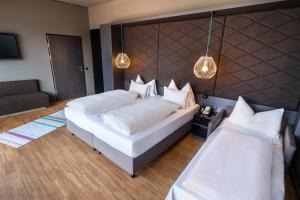 een slaapkamer met 2 bedden en een bank bij aDLERS Hotel Innsbruck in Innsbruck