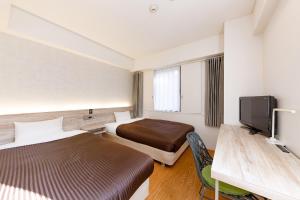 a hotel room with two beds and a flat screen tv at The OneFive Fukuoka Tenjin in Fukuoka
