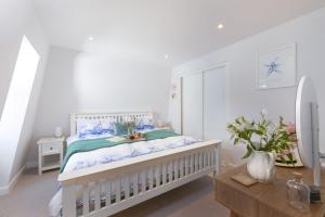 a white bedroom with a bed with blue and green sheets at Fowey Penthouse, Fowey in Fowey