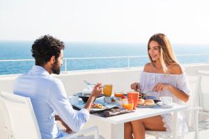 Un uomo e una donna seduti a un tavolo che fanno colazione di Dimora Talenti a Polignano a Mare