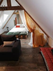 a room with a bed and a couch in a attic at D'ici et d'ailleurs in Raids