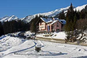 ein Haus auf einem schneebedeckten Hügel mit Bergen im Hintergrund in der Unterkunft Hotel Mooserkreuz in Sankt Anton am Arlberg
