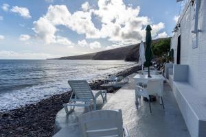 una playa con sillas, mesas y sombrilla en Casa Lucia en Playa Quemada