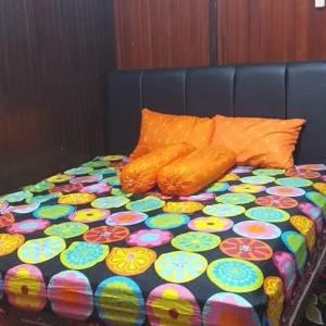 a bed with a colorful comforter and pillows at Mimi Guest House Syariah Pangkalan bun in Pangkalan Bun