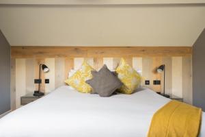 a large bed with yellow pillows on top of it at Mill on the Exe in Exeter