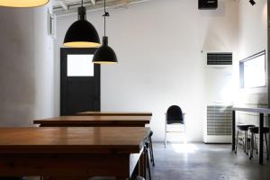 uma sala de jantar com mesas de madeira e luzes de pendentes pretas em hostel mog em Ueda