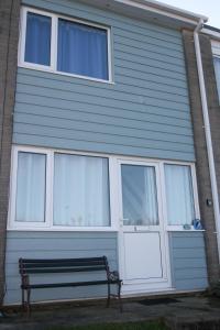 a bench sitting in front of a house at Freshwater Bay Holiday Cottages in Pembroke