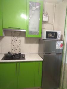 a small kitchen with green cabinets and a refrigerator at Хорошая однокомнатная квартира в центре города in Shostka
