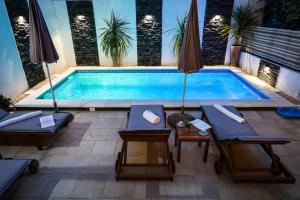ザダルにあるApartment Rustica Zadar with exclusive use of the pool-ground floorのパティオ(椅子、パラソル付)