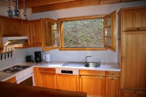 een keuken met houten kasten, een wastafel en een raam bij Aeolus MOUNTAIN & QUIET chalet 12 pers by Alpvision Résidences in Veysonnaz