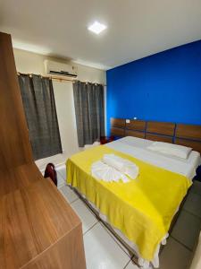 1 dormitorio con cama amarilla y pared azul en Hotel Borari, en Alter do Chao